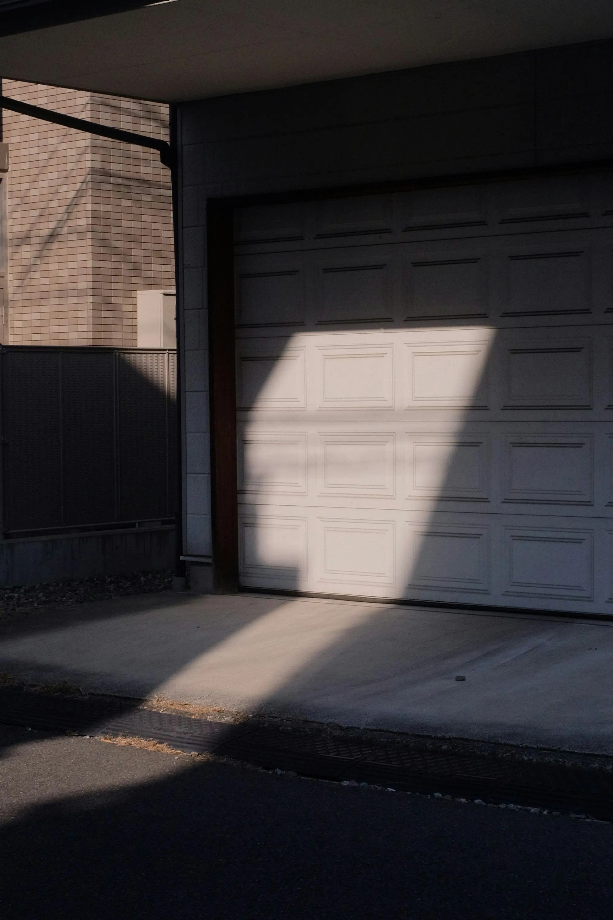Dark garage door half in shadow beside a concrete floor